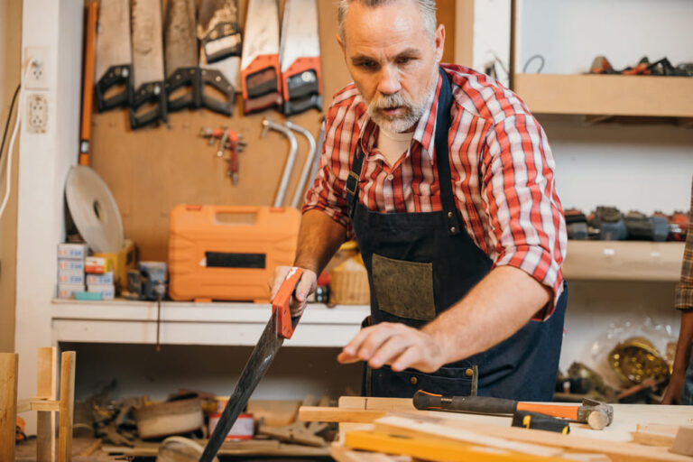 man aan het werk met verschillende soorten zagen voor hout
