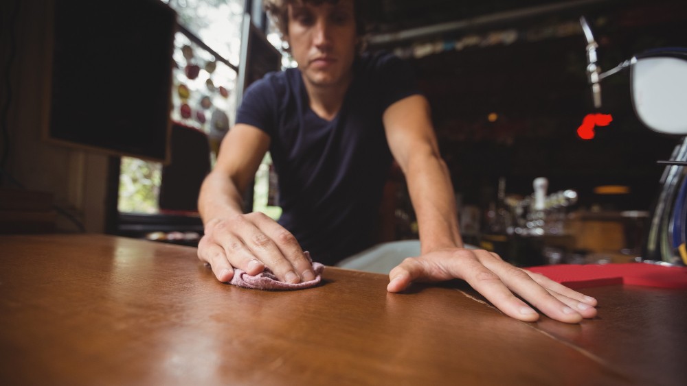 Houten meubels onderhouden door tafel af te nemen met doek tijdens dagelijks schoonmaken