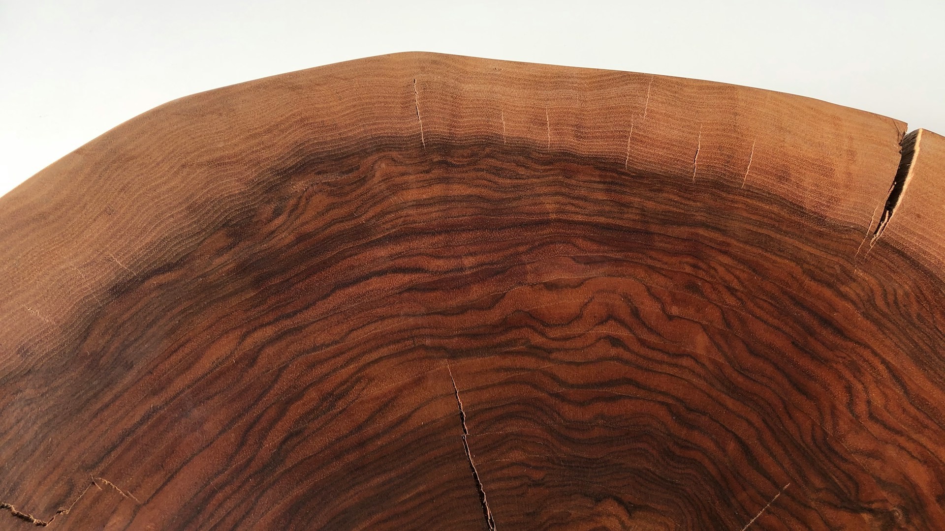 Houtstructuur close-up van donkerbruin hout met golvende houtnerf en zichtbare scheuren in het oppervlak